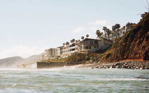 Oceanfront homes in Malibu California with palm trees on a sunny day