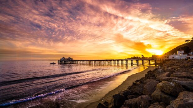 Malibu California pier at sunset with vibrant sky and ocean waves