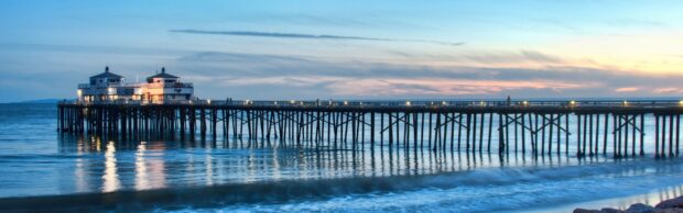 Malibu California pier extending into the ocean at sunset with calm waves and clear sky