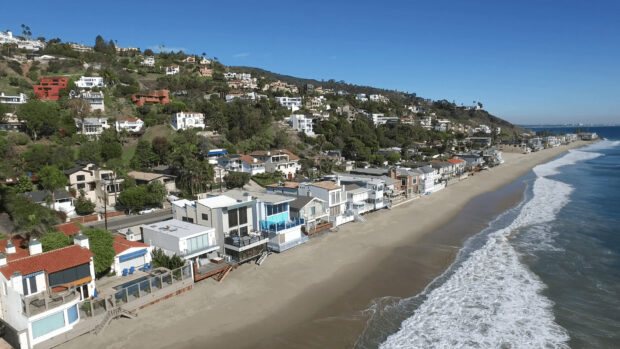 Malibu California houses along the beachfront with clear blue sky and ocean waves