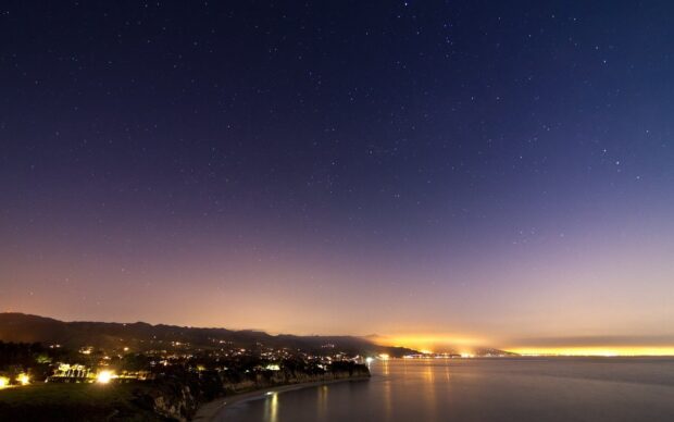 Malibu California night sky with stars over the coastline and city lights