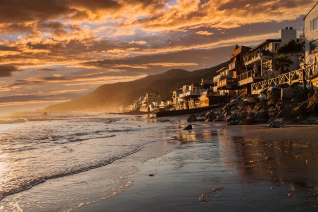 Malibu coastline with houses under a dramatic sunset sky in California