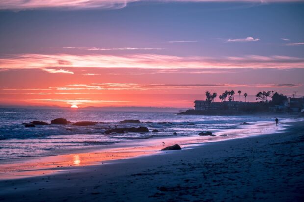 Sunset over Malibu coast with vibrant sky and waves on the beach