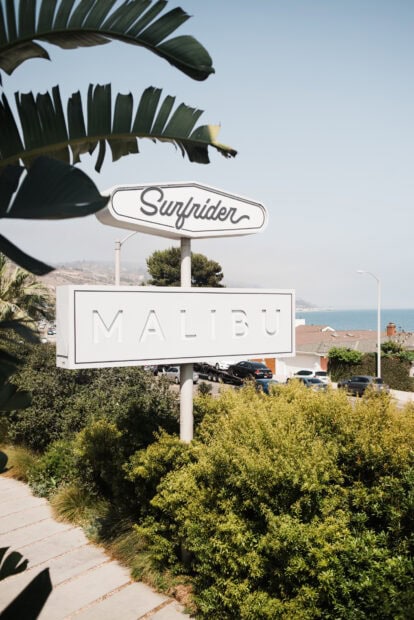 Surfrider sign with Malibu in the background surrounded by greenery and ocean view