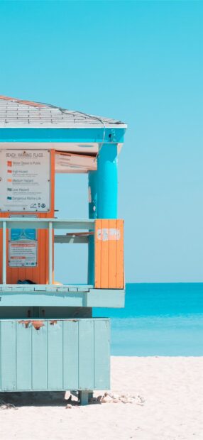 A lifeguard tower in Malibu California stands on the sandy beach under a clear blue sky