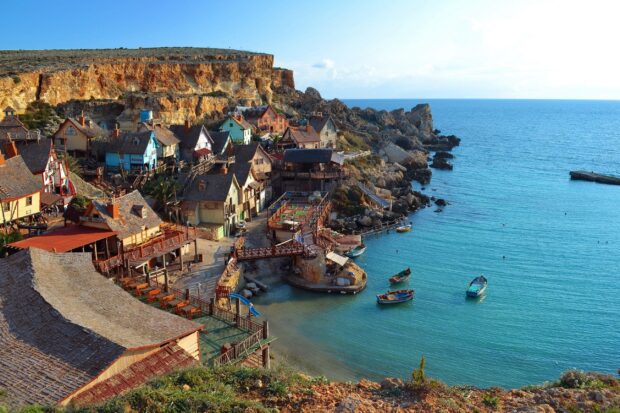 A scenic view of Malta coastline with colorful houses and boats on the clear sea water