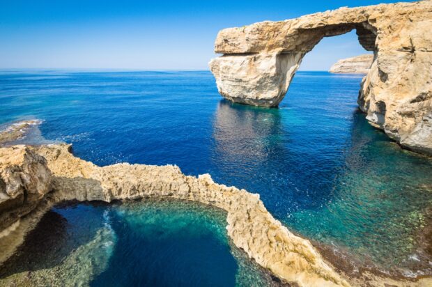 Natural rock formation in Malta sea with clear blue water and sky