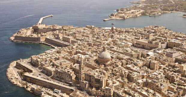 A scenic aerial view of Malta showing historic buildings and the coastline with the Malta landmark dome visible