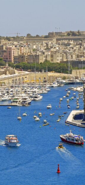 Scenic view of Malta harbor with boats and historic buildings along the coastline