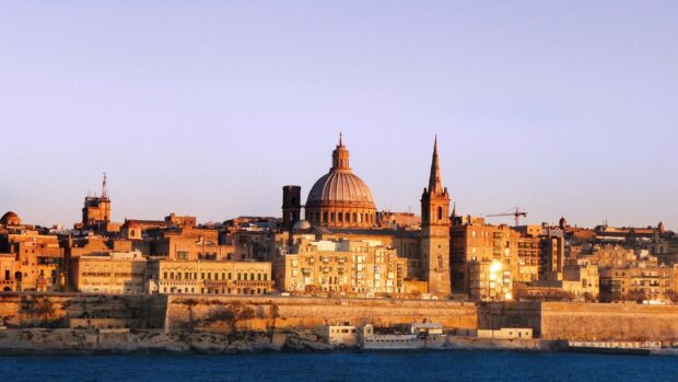 Historic Malta city skyline with cathedral dome at sunset in warm light
