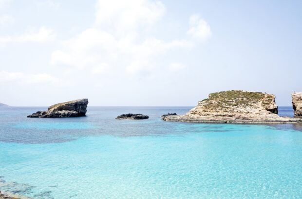 Clear turquoise sea with rocky islands in Malta under a bright sky
