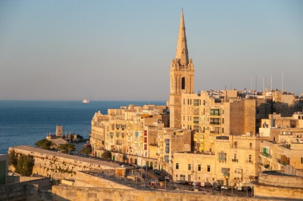 Historic Malta cityscape with the sea and church tower during golden hour