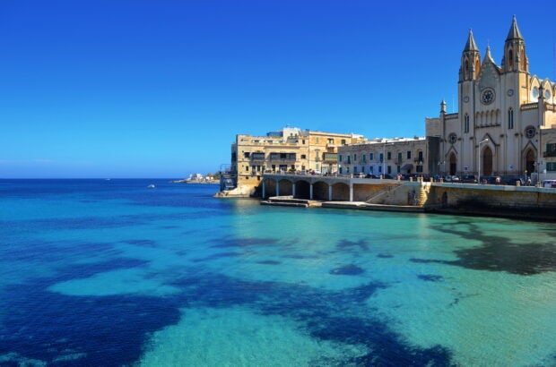 Historic Malta coastline with clear blue sea and traditional buildings by the shore
