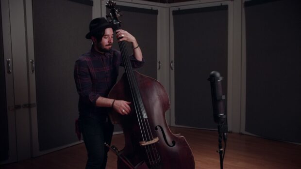 A man is playing double bass in a soundproof music studio with a microphone nearby, HD Desktop Wallpaper