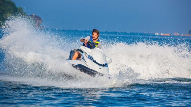 A man is riding a jet ski with water splashing around him on a bright day, HD Desktop Wallpaper