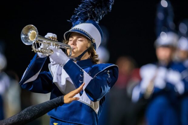 A marching band trumpet player is focused while performing during a night event, 2K Desktop Wallpaper