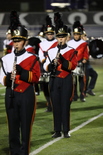 Several marching band musicians are performing with clarinets on the field during a night event, 2K Mobile Wallpaper
