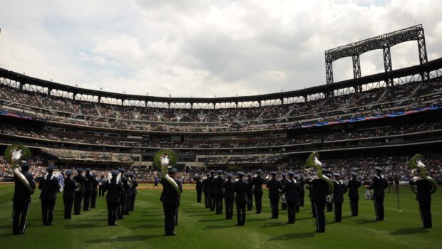 A marching band is performing in formation on a sports field filled with spectators, HD Desktop Wallpaper