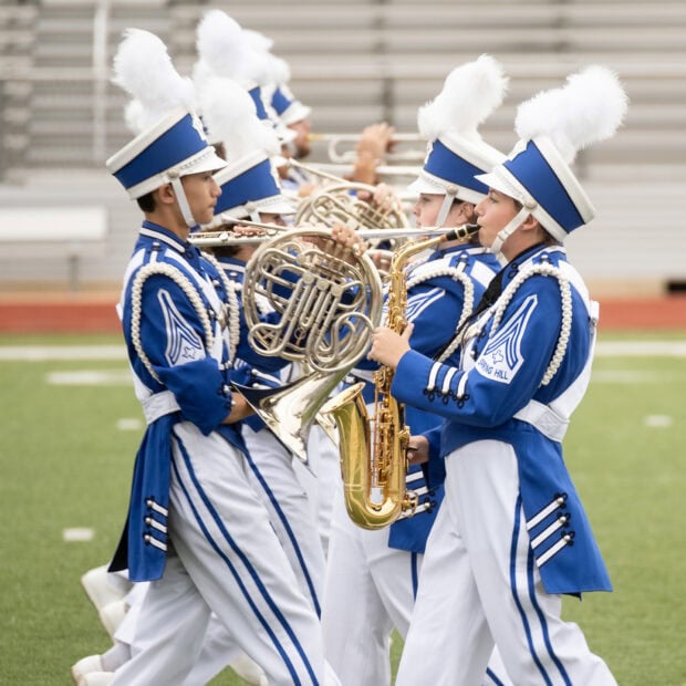 A marching band plays instruments in blue uniforms on a field during a performance, HD Mobile Wallpaper