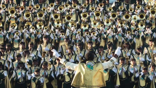 A marching band performs music outdoors led by a conductor, HD Desktop Wallpaper