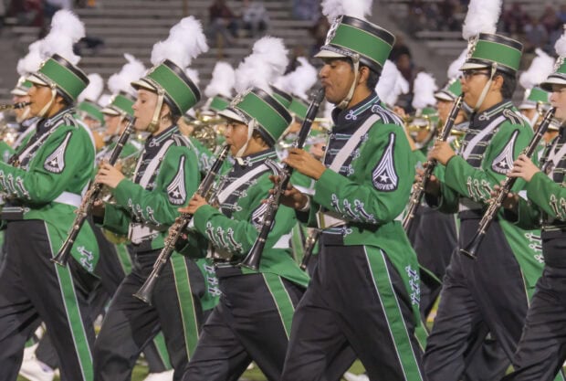 A marching band dressed in green uniforms is playing clarinets while marching, HD Desktop Wallpaper