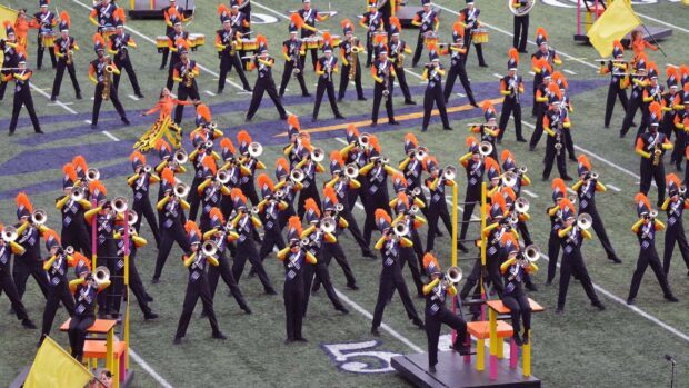 A marching band performs a complex formation with trumpets and drums on the field, 2K Desktop Wallpaper