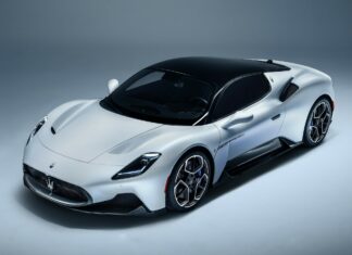 A sleek Maserati sports car with a white body and black roof in a studio setting