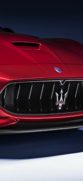 Close up of Maserati front grille with red hood and badge on dark background