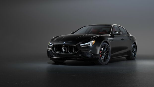 Black Maserati sports car parked in a studio with sleek design and red interior