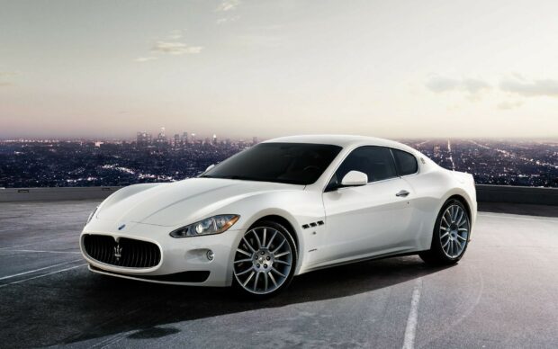 White Maserati sports car parked with cityscape in the background