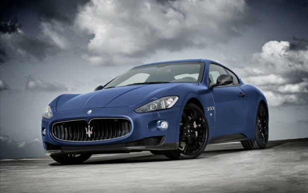 Blue Maserati sports car in a dramatic cloudy sky setting
