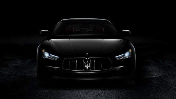 Front view of a luxury Maserati car with headlights on in a dark setting