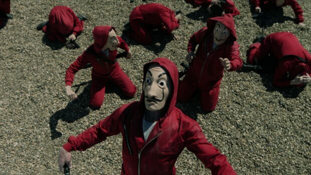 Several masked characters in red suits are seen on a pebble ground in a Money Heist scene, HD Desktop Wallpaper
