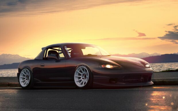 A sleek Mazda car parked by the lakeside during sunset with mountains in the background, 2K Desktop Wallpaper