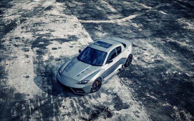 A sleek silver Mazda is parked on a weathered concrete surface with distinct textures and shadows, HD Desktop Wallpaper