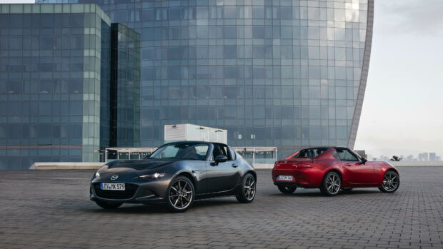 Two Mazda sports cars are parked on a large paved area near a glass building under a clear sky, 4K Desktop Wallpaper