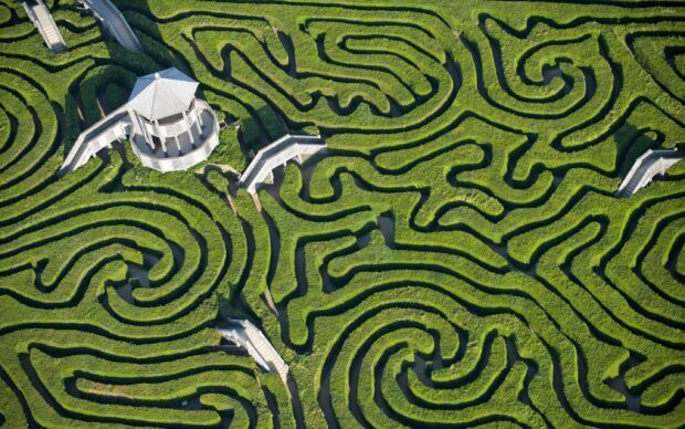 Aerial view of a green maze with pathways and a central gazebo structure