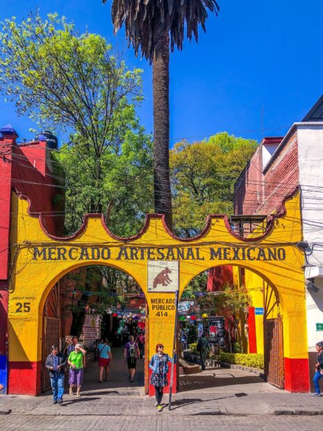People walking under the yellow arch of the Mexican artisan market in Mexico City, HD Desktop Wallpaper