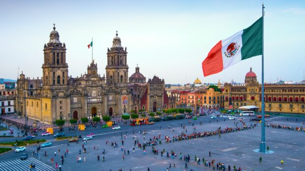 A large Mexican flag waves over the plaza near the historic cathedral in Mexico City, HD Desktop Wallpaper