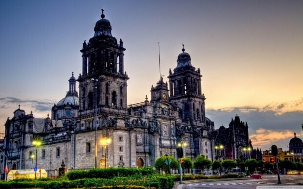 The Mexico City cathedral stands prominently with lit street lamps under a colorful sunset sky, 2K Desktop Wallpaper