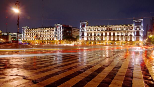 The historic buildings of Mexico City are beautifully illuminated at night with light trails from passing cars, 2K Desktop Wallpaper