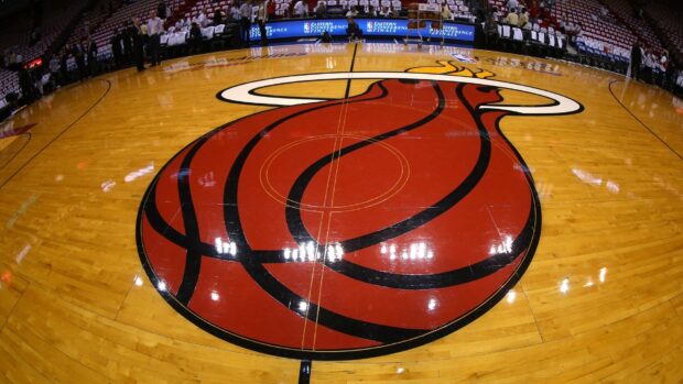 The Miami Heat logo at center court on a polished basketball hardwood floor