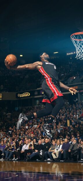 Miami Heat player jumping for a dunk during a basketball game in an arena with a crowd