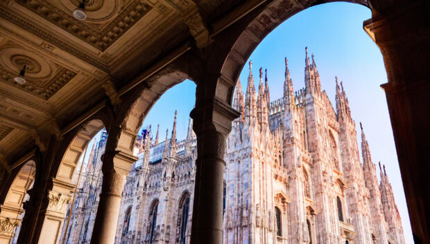 A detailed view of Milan cathedral architecture framed by stone arches at sunset