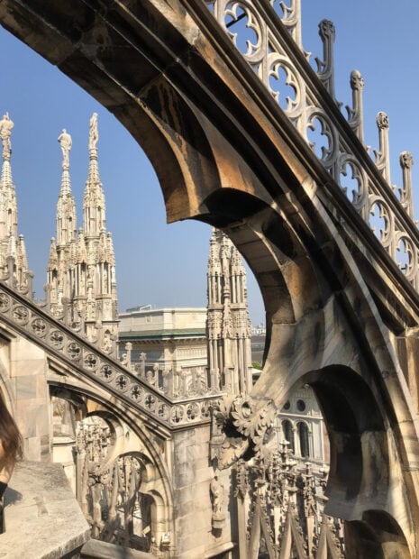 Gothic architecture details in Milan with ornate arches and spires under clear blue sky