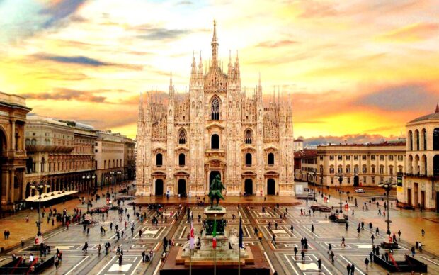 Milan is showcasing a grand cathedral with a crowded square during sunset
