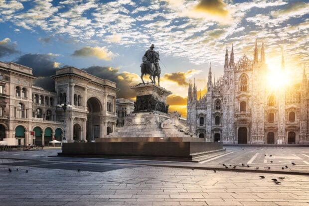 Statue of Milan with historic buildings and sunrise sky in Milan city center