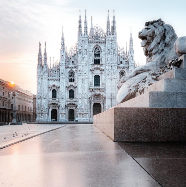 Stunning Milan architecture with a lion statue in the foreground at sunrise