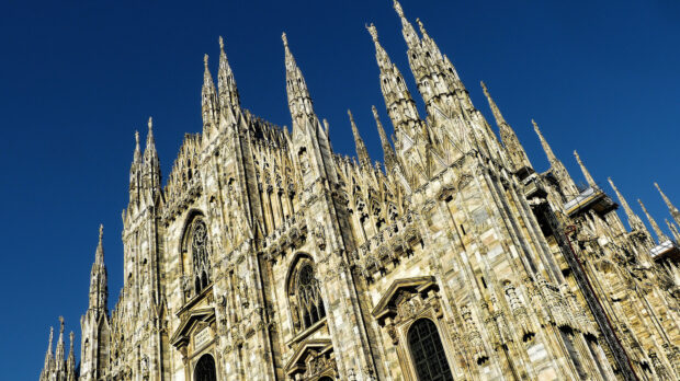 The detailed architecture of Milan Cathedral under clear blue sky with Gothic style elements