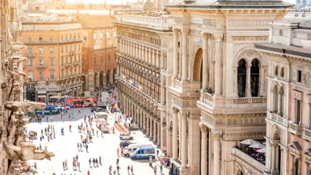 A busy Milan street scene with historic architecture and crowds of people in bright daylight